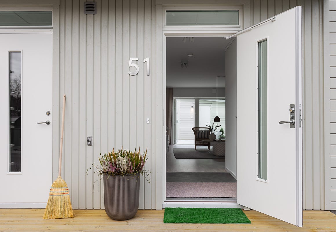 Foto på ett grått hus med en öppen dörr