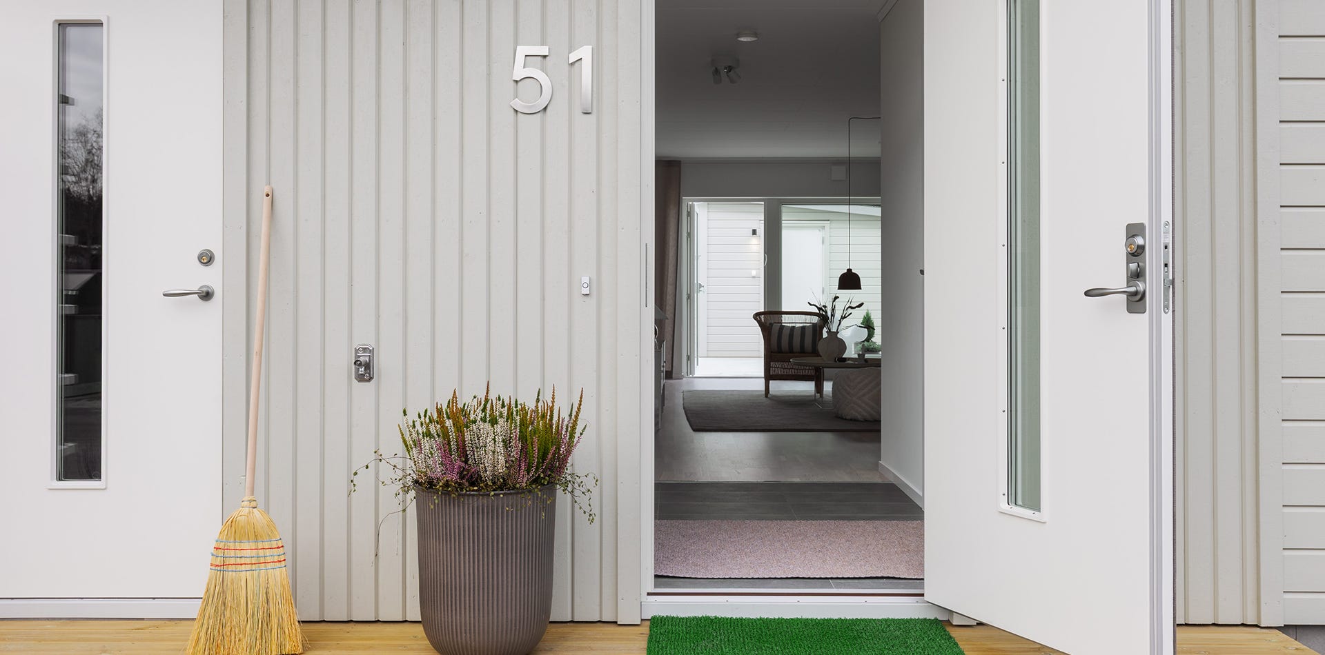 Foto på ett grått hus med en öppen dörr