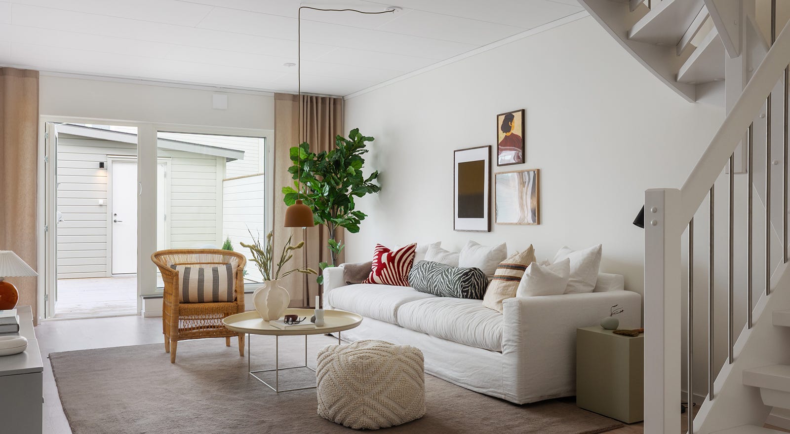 Foto på ett vardagsrum med en vit trappa i förgrunden