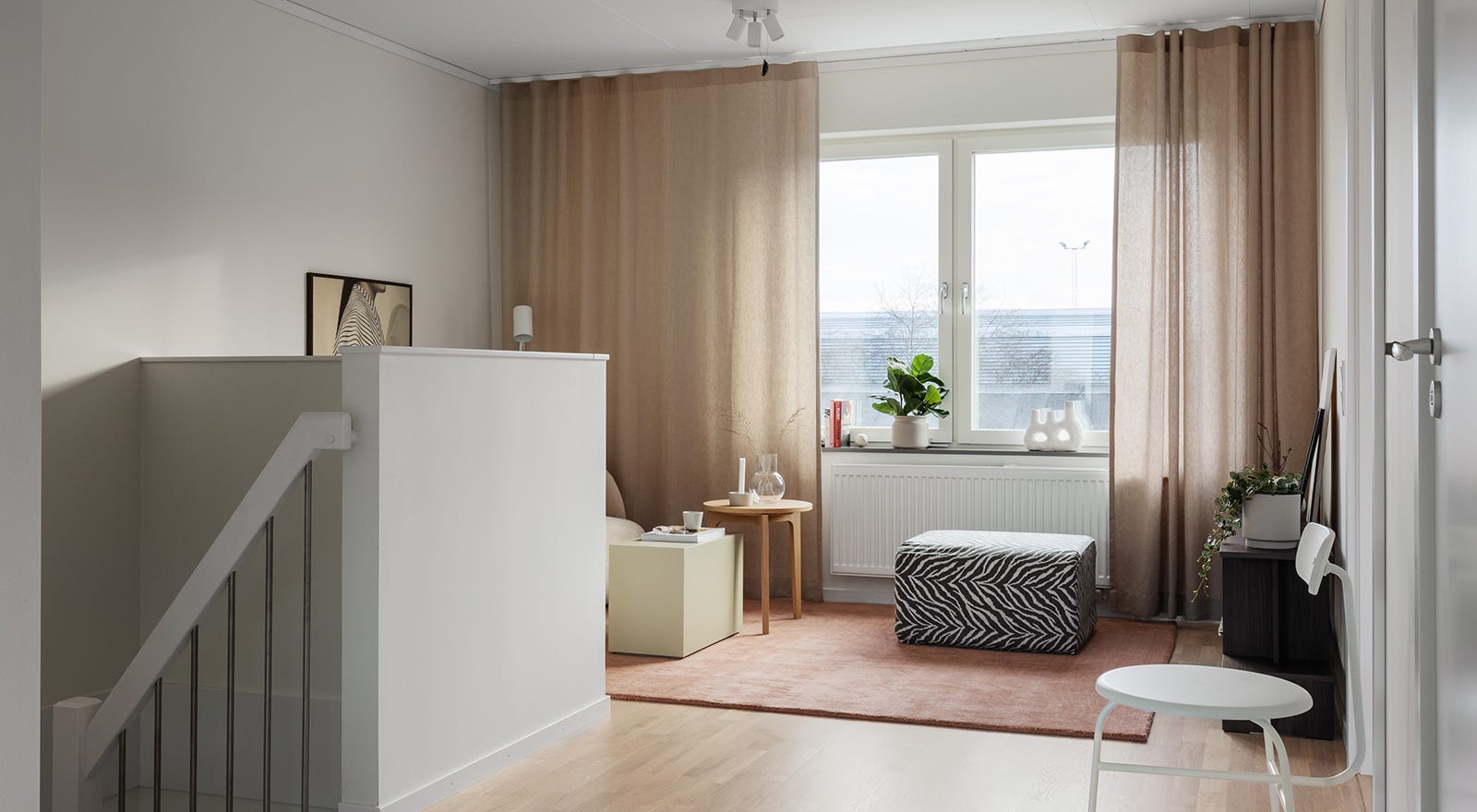 Foto på ett allrum med en trappa i förgrunden