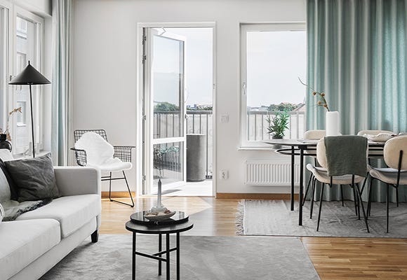 Foto på en grå soffa, ett svart matbord och överblick ut till balkongen