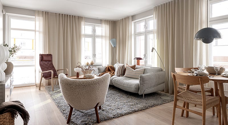 Foto på ett vardagsrum med en grå soffa och beige gardiner