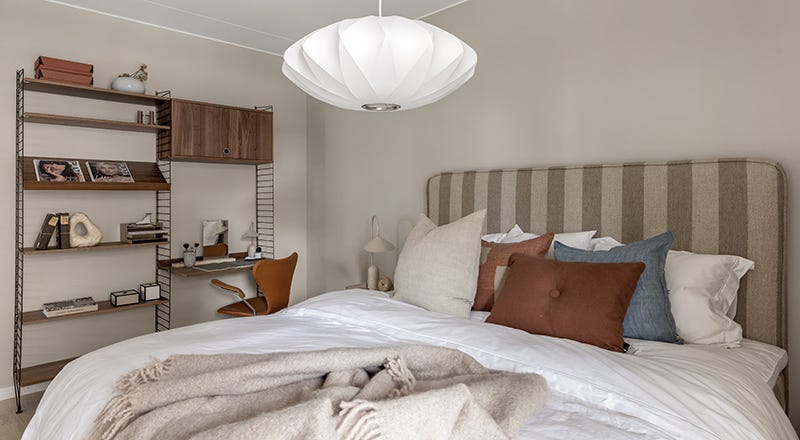 Foto på ett sovrum med en stor dubbelsäng och en Stringhylla vid väggen