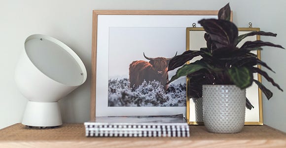 Närbild på byrå med tavlor och lampa ovanpå