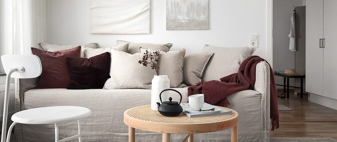 Foto på en beige soffa med ett litet sidobord 
