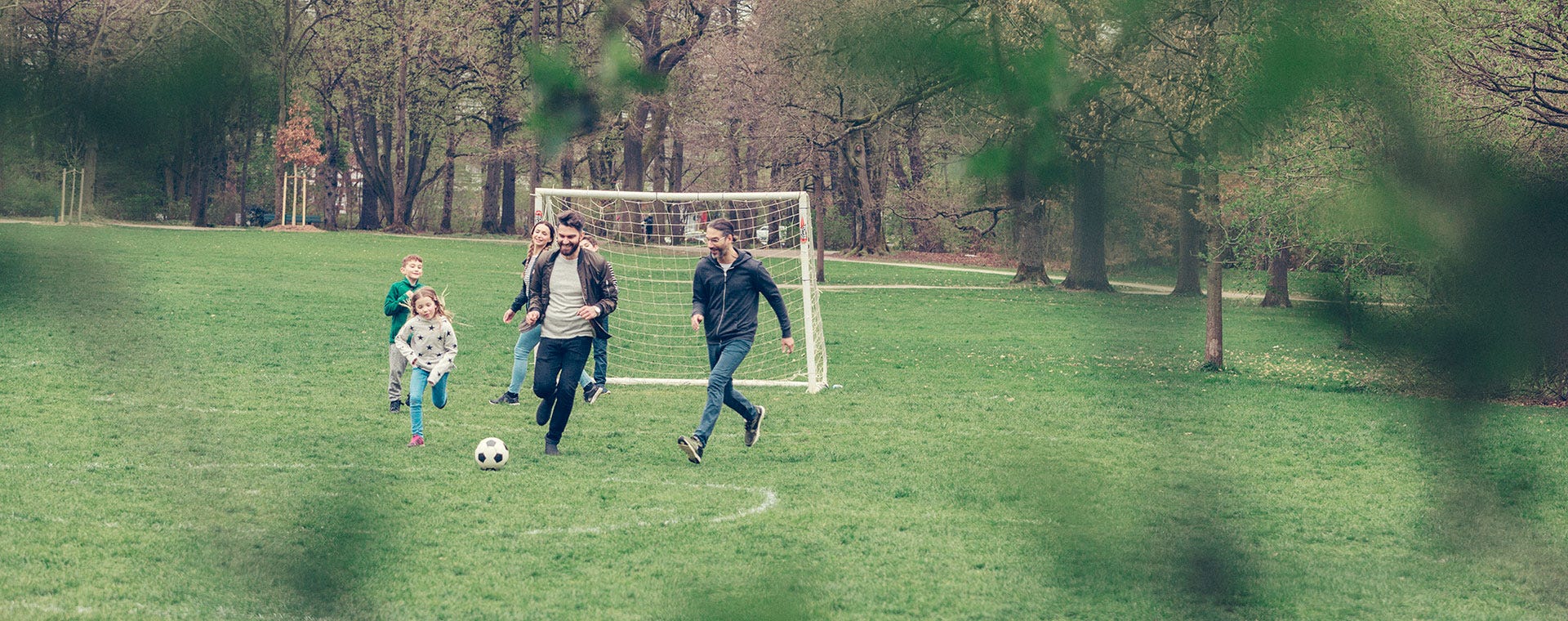 Familj och vänner som spelar fotboll med barn