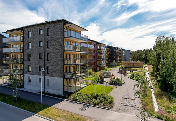 Foto på lägenhetsbyggnad med lekplats på baksidan