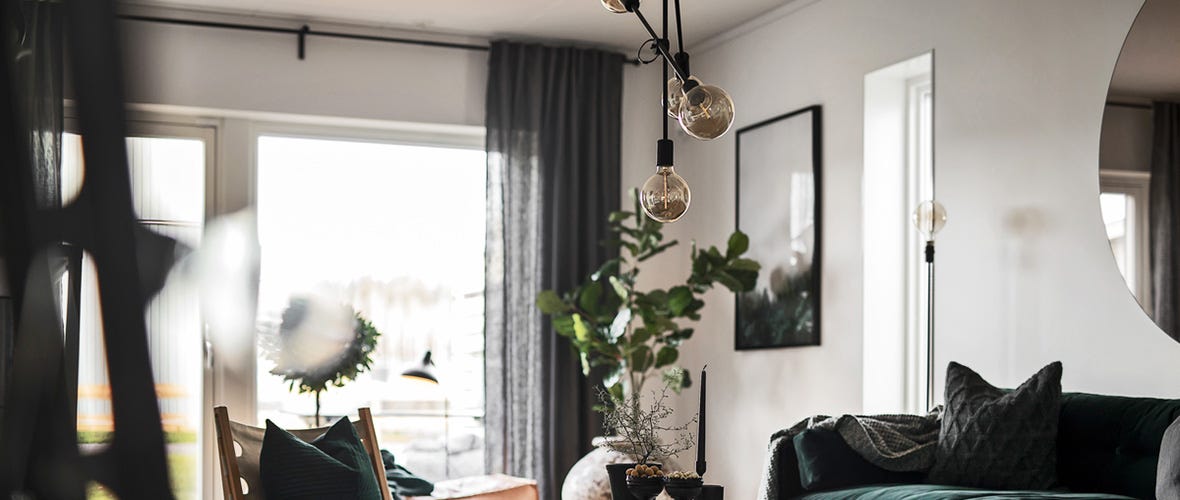 Vardagsrum med lampor, växter och soffa