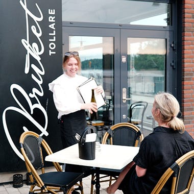 Foto på kund och servitris på restaurang Bruket i Tollare